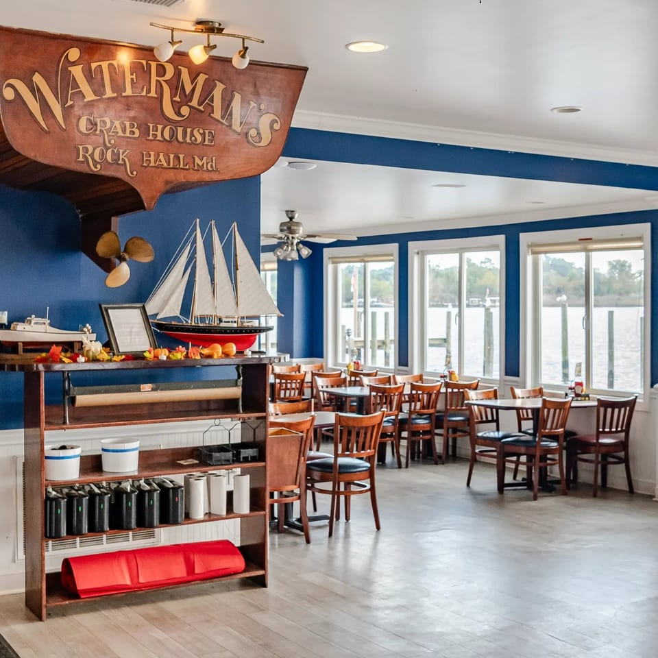 Nauterm's Crab House dining room features nautical decor, wooden tables, blue walls, and waterfront windows.