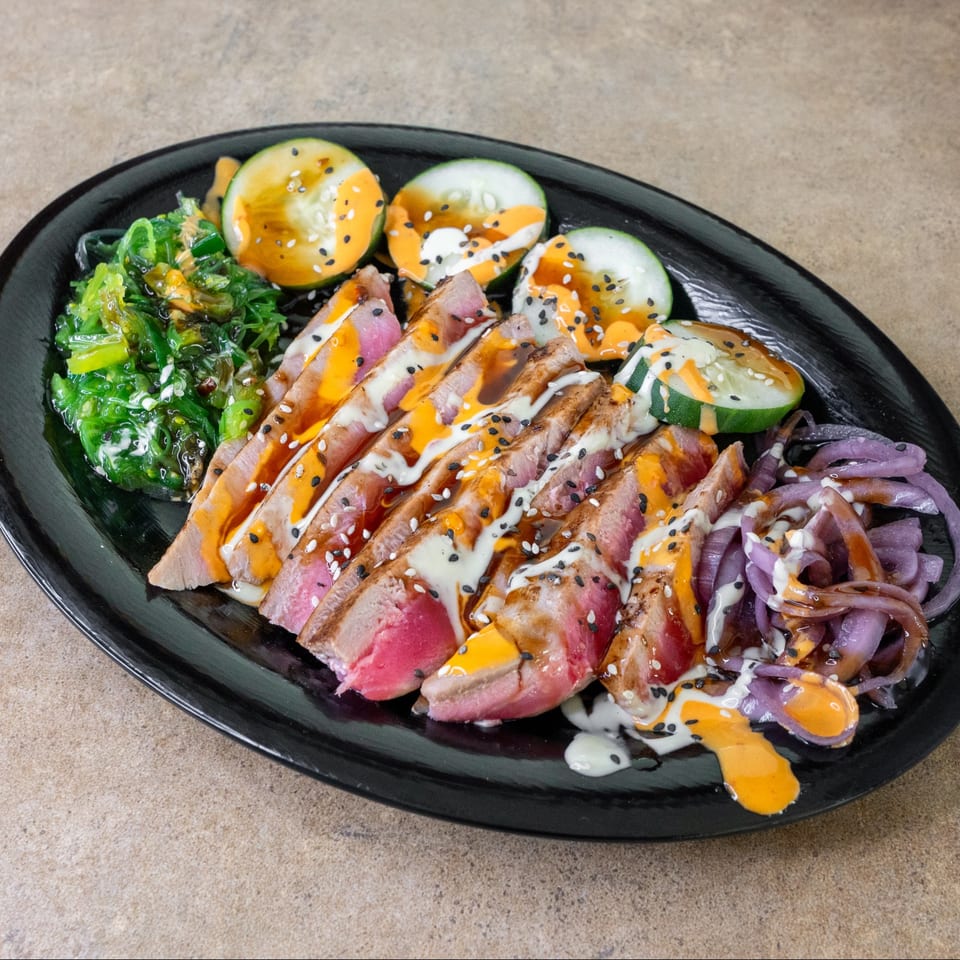 Sliced ahi tuna with cucumber and seaweed salad.